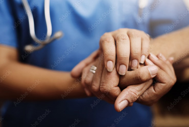 Doctor in blue scrubs holding hands with a patient