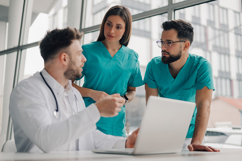 Medical team analyzing patient data on laptop in hospital. 