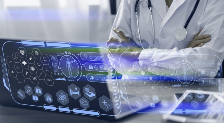 Doctor sitting at desk looking at laptop.