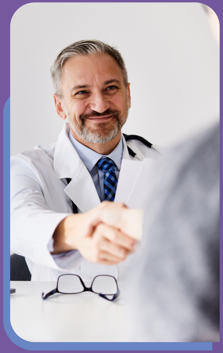 Doctor shaking hands with patient across a table.