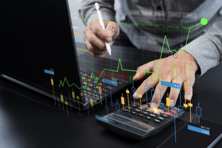 Businessman analyzing stock market chart and financial data using laptop and calculator. Digital candlestick graph overlay represents investment, trading, finance, and economic analysis concept.